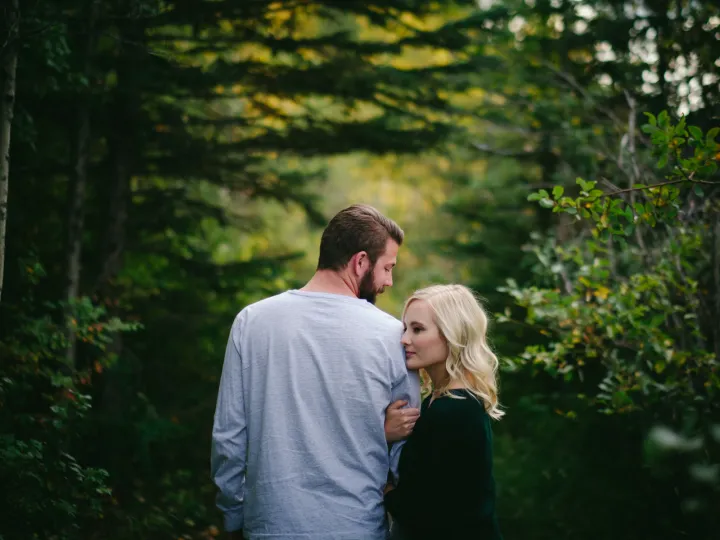 Engaged couple walking together into a green forest
