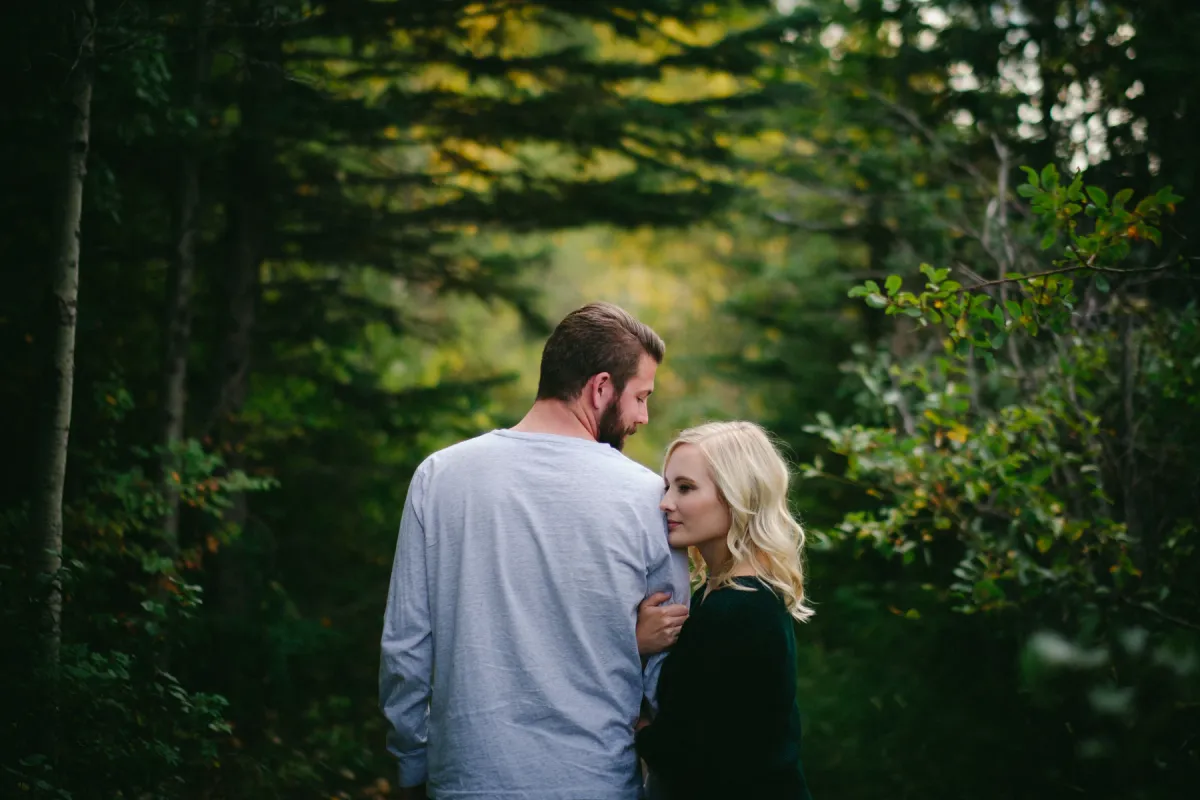 Engaged couple walking together into a green forest