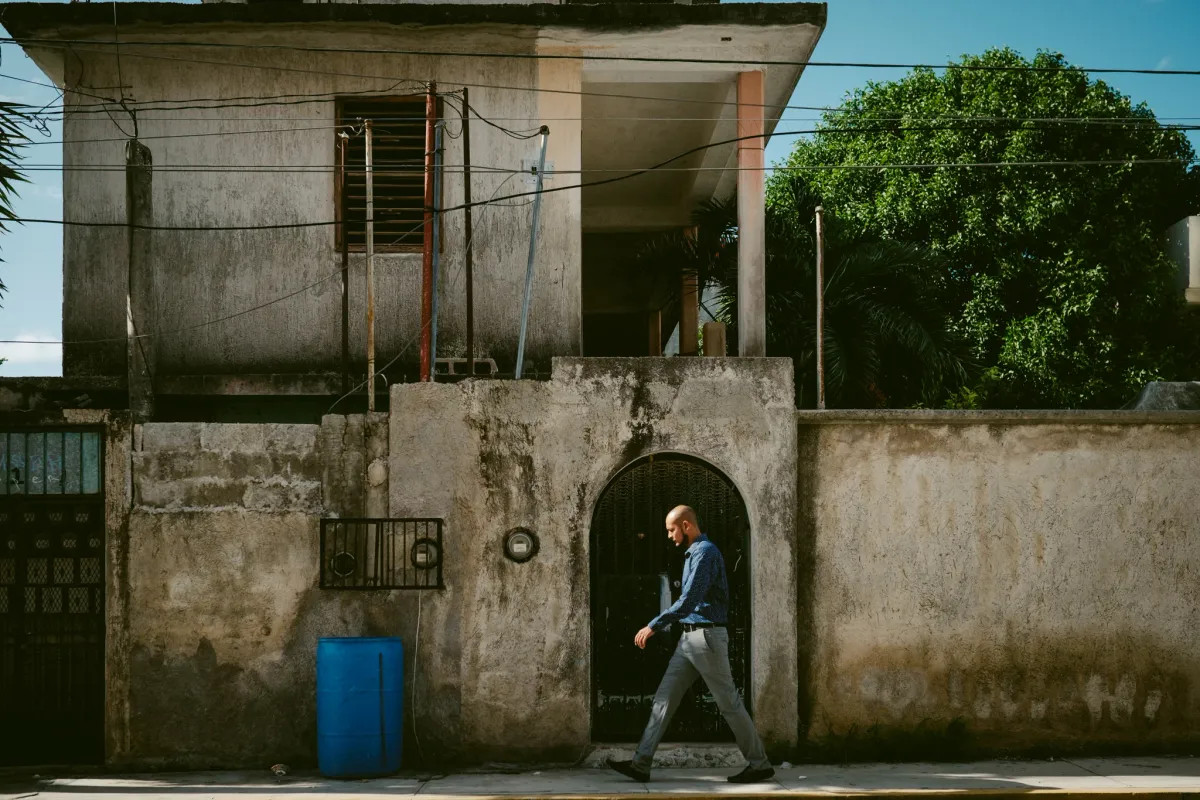 Person walking past a concrete wall with a dark arched doorway