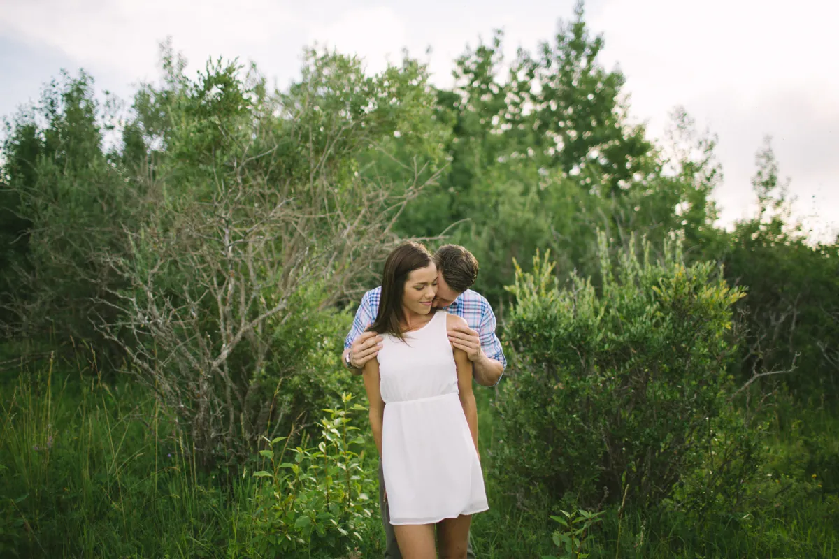 Couple embracing outdoors with the woman in a white dress during an engagement session
