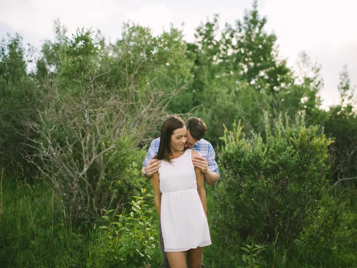 Couple embracing outdoors with the woman in a white dress during an engagement session