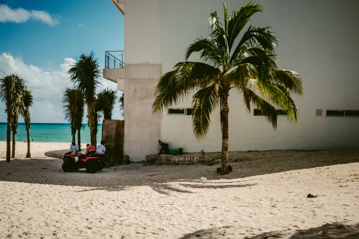 Red chairs beside white walls and palm trees on a bright coastal street