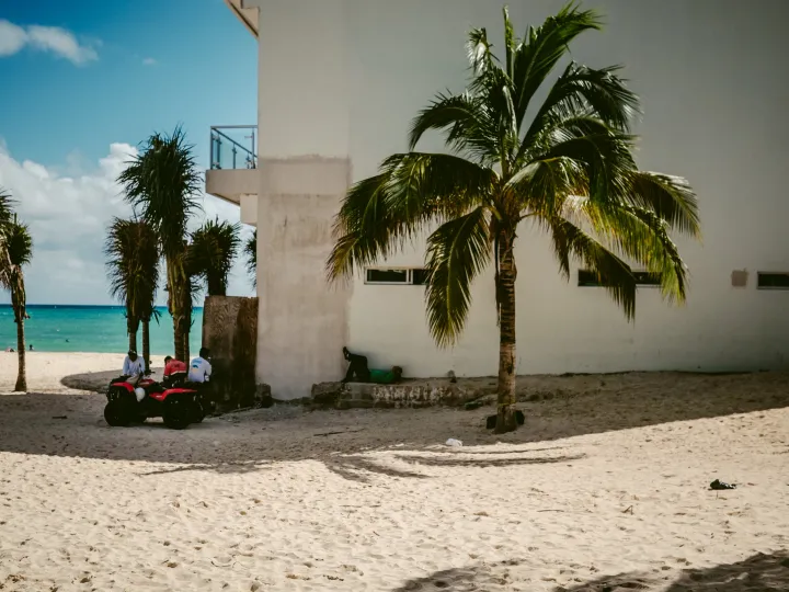 Red chairs beside white walls and palm trees on a bright coastal street
